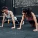 Man and woman doing pushups while smiling during a workout inside a Mexico City gym.